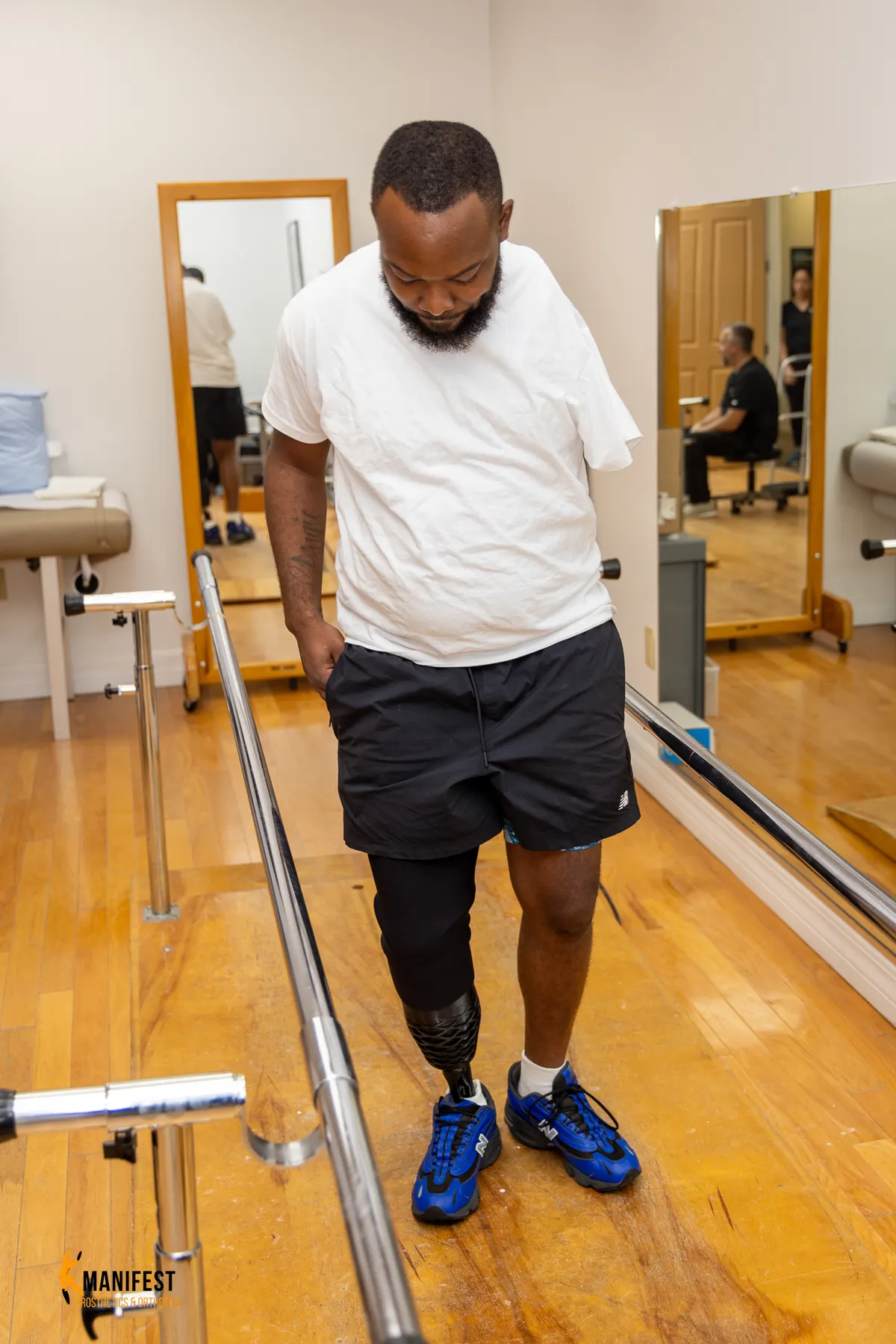 Darius Rush walking with his Manifest-built prosthetic leg between parallel bars.