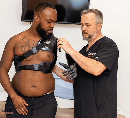 Clinician fitting an upper-body harness on a patient.