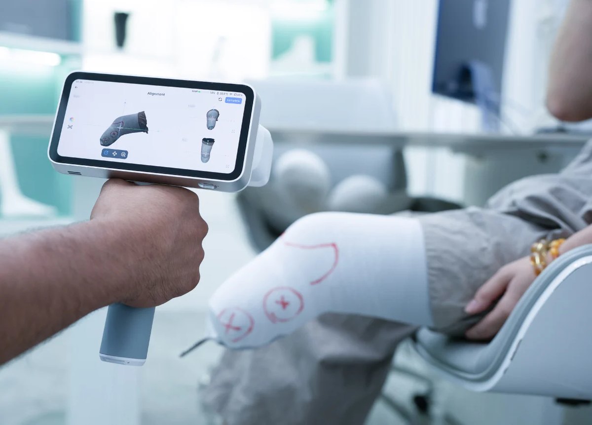 Clinician using a handheld 3D scanner to digitally capture a patient&rsquo;s limb for custom device design.