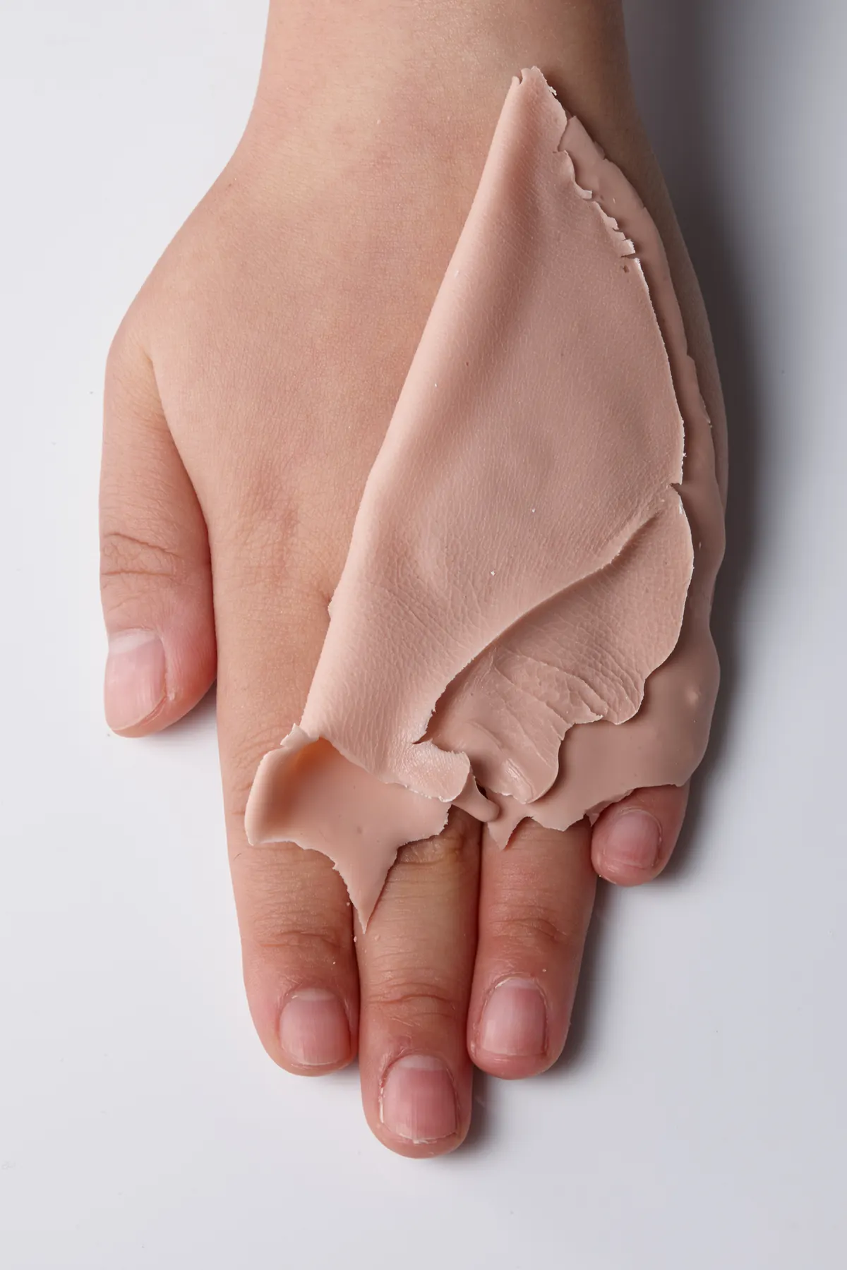 Close-up of a hand-painted silicone restoration showing color matching, veining, and lifelike skin detail.
